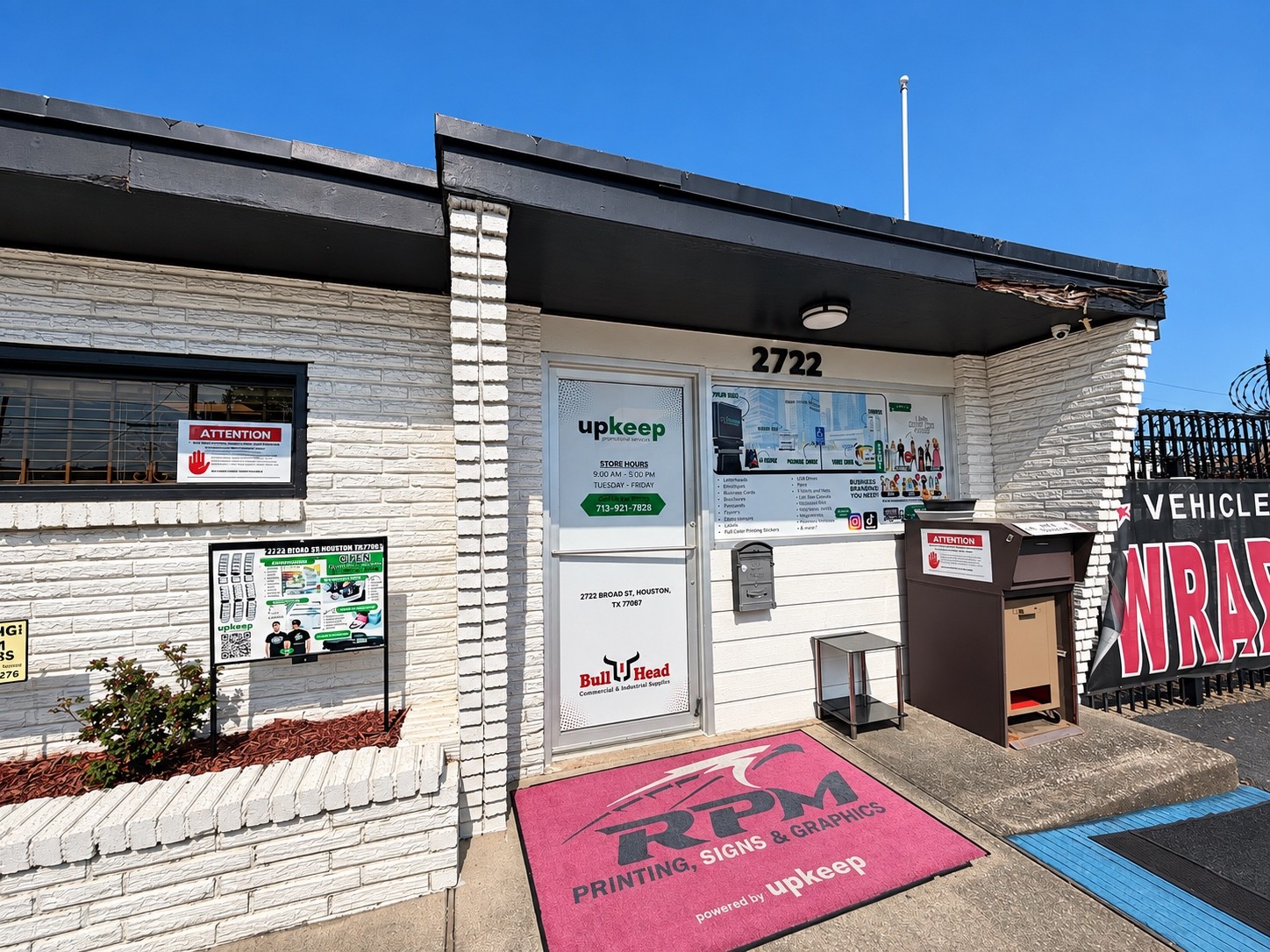 UpKeep storefront entrance with white brick, branded door and building number 2722